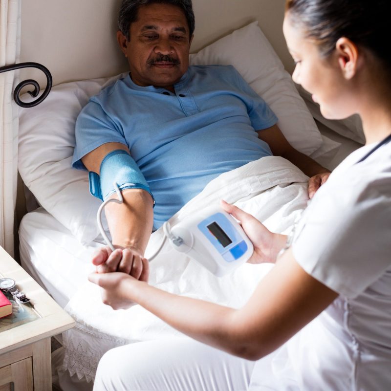 Doctor checking blood pressure of senior woman at home